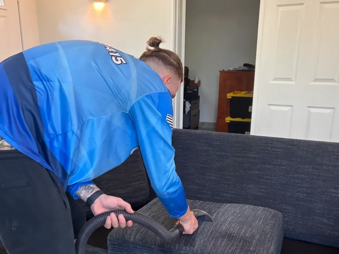 Technician cleaning a fabric sofa cushion with an upholstery hand tool